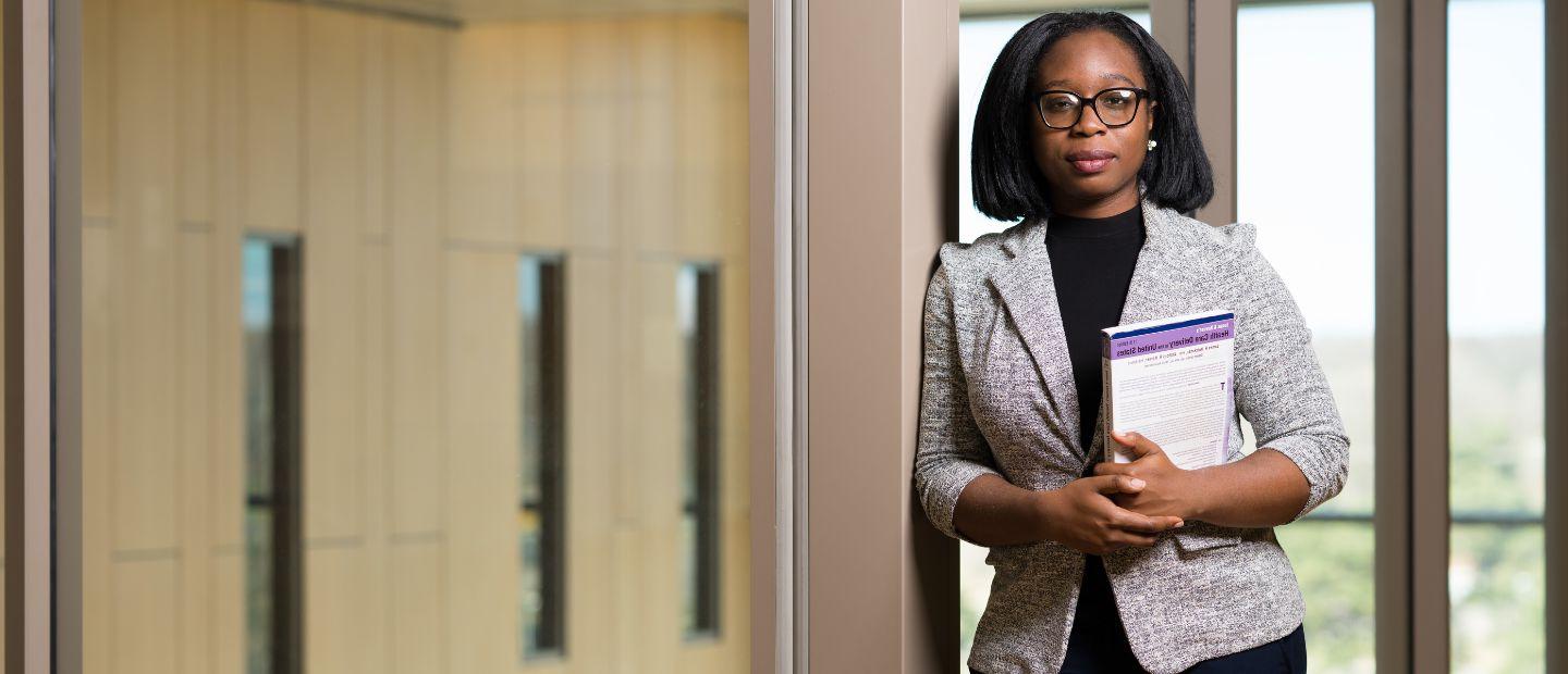 A professional woman holding a notebook, looking at the camera.